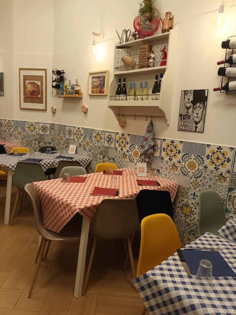 Interno della trattoria: maioliche colorate, tovaglie a quadretti e il poster di Totò