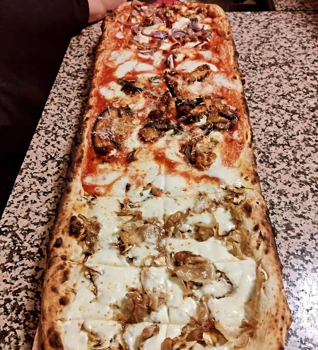 Un metro di pizza appena sfornato sul bancone di Tutta 'Nata Storia